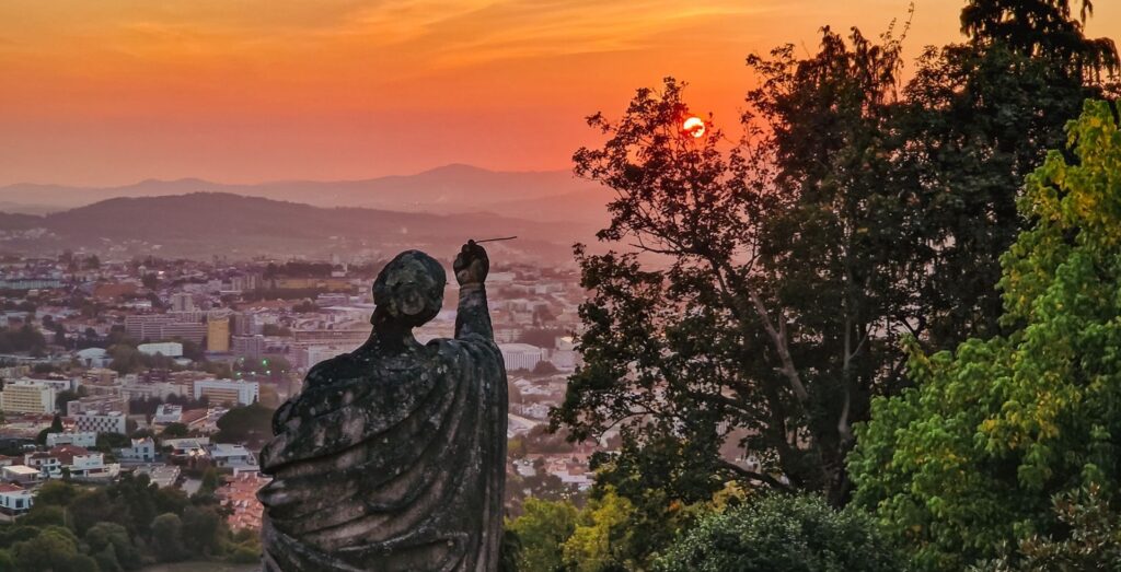 Statue seen from behind, overlooking the city of Braga at sunset, Portugal destinations
