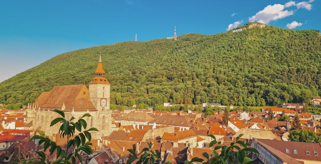 Medieval town with towering church and a forest-covered mountain in the back - Visit Brașov, Romania
