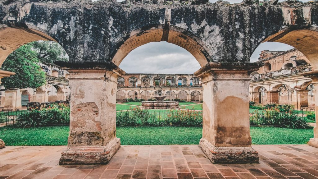 Arches opening onto a courtyard with a fountain at its center, colonial ruins in Antigua Guatemala