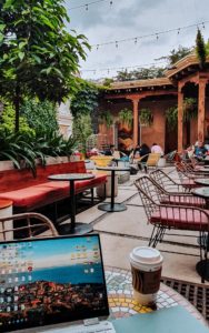 A laptop on a table and more table and colorful seats surrounded by plants in a courtyard at Starbucks in Antigua Guatemala