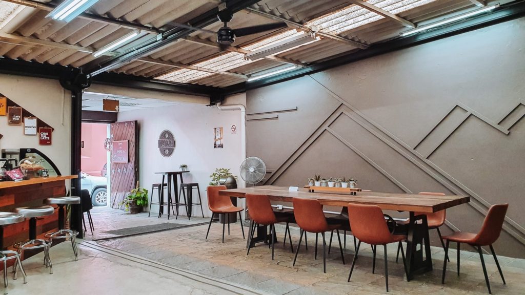 A large table with chairs and a small counter with stools at a minimalist cafe in Antigua Guatemala