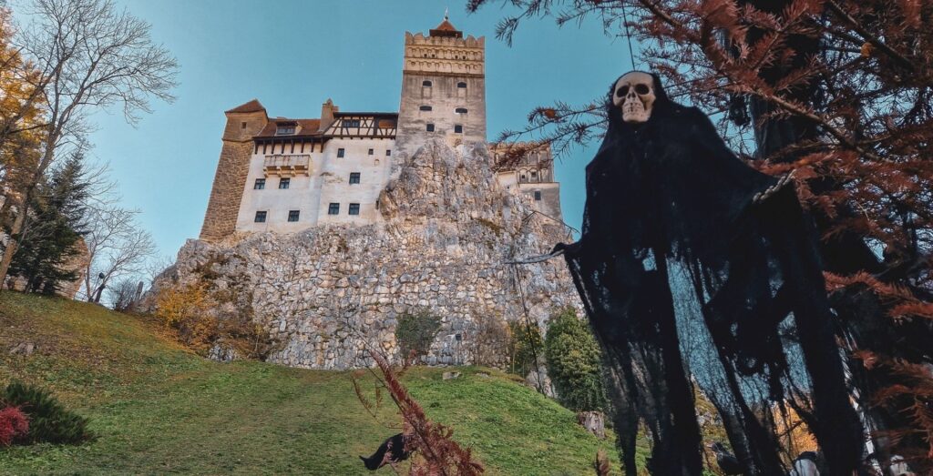 A skeleton in a black robe hangs from a tree in front of Bran Castle in Romania