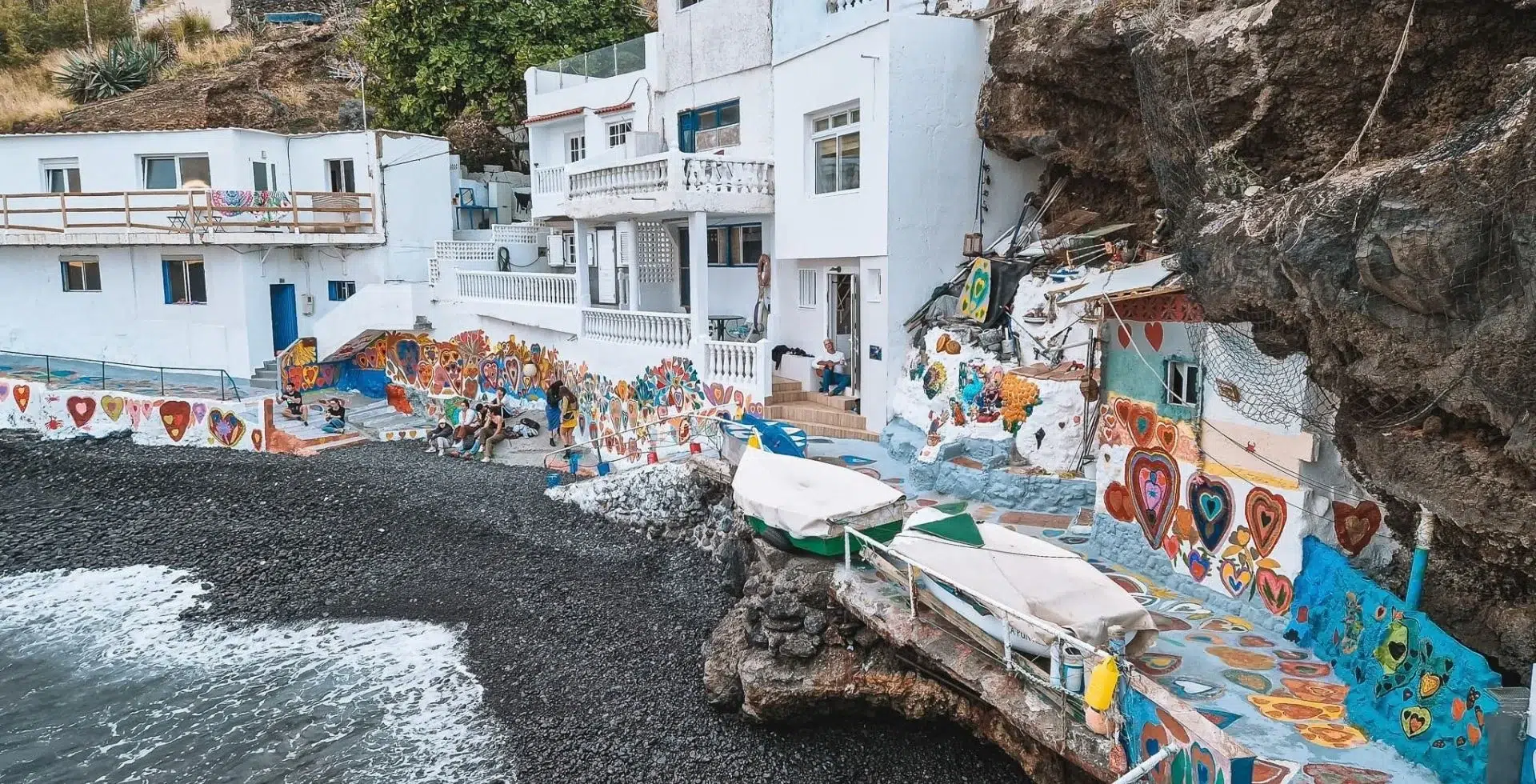 A small bay with whitewashed houses covered in colorful heart paintings