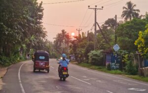 Weligama, Sri Lanka TukTuk and scooter on a road in Sri Lanka at sunset
