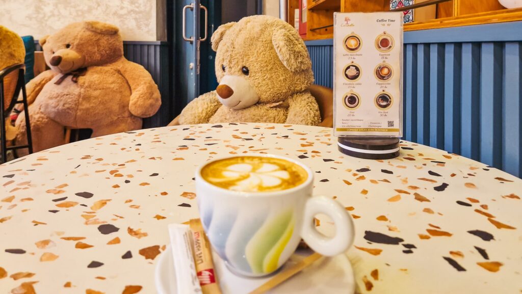 A cup of cappuccino on a table surrounded by teddy bears