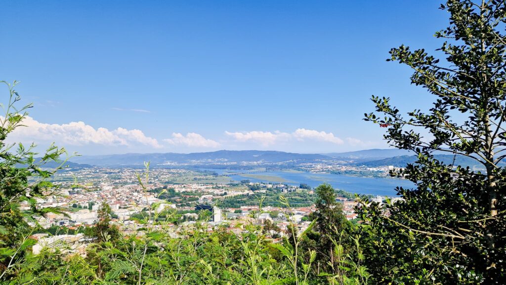 Viana do Castelo, Camino Portugués Day 3 View over a town and river valley from a hillside, with distant mountains and a clear blue sky.