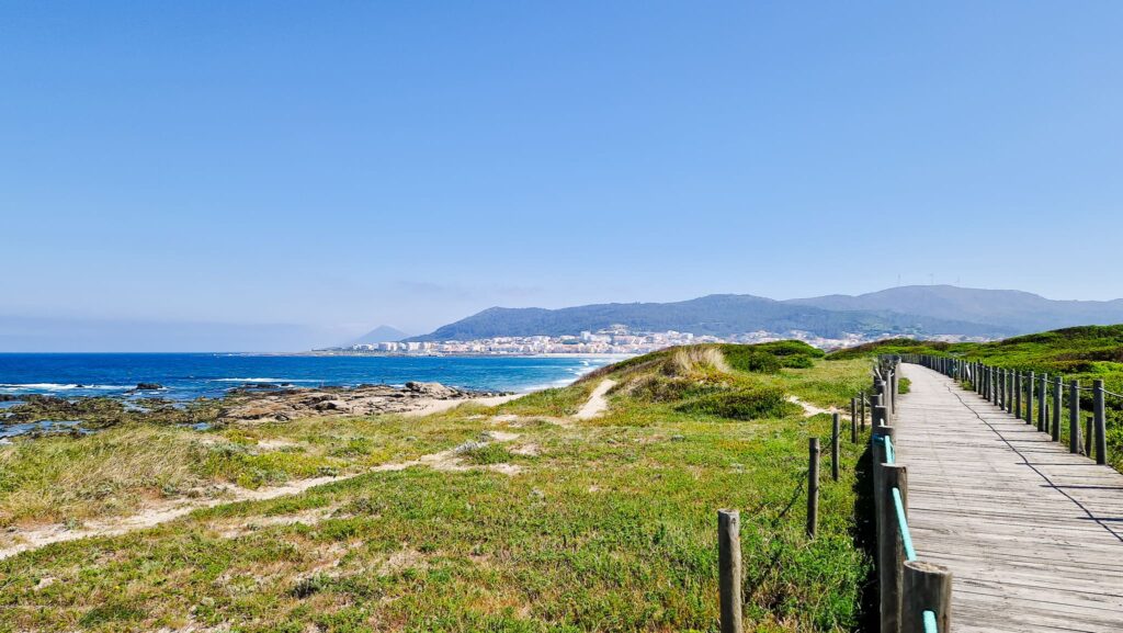 Boardwalk - Camino Portugues from Porto Wooden boardwalk along coastal dunes toward a blue sea and distant town on the horizon, Camino Portugués de la Costa