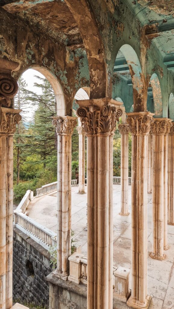 Tskaltubo Row of carved stone columns with volute capitals under arches in a dilapidated pavilion, with trees outside. Tskaltubo, Georgia travel destinations