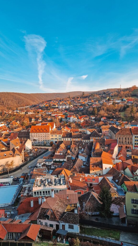 20241203_151317 A hillside town with densely packed colorful houses and red roofs under a clear blue sky at sunset/tlate afternoon light. Romania travel destinations