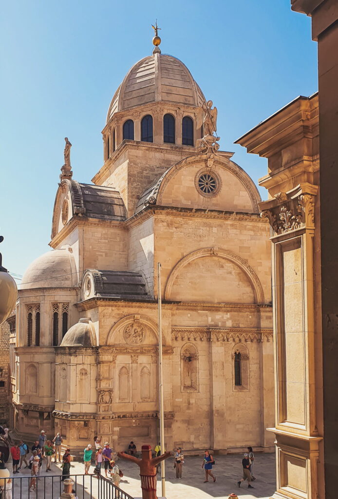 Cathedral of St. James Beige stone church with a large central dome and ornate arches, in a sunny square with visitors nearby. Top sight on a Šibenik day trip