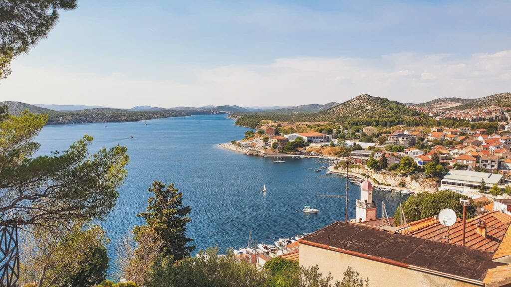 View St. Michael's Fortress Panoramic view of a coastal city framed by the branches of a tree in Croatia