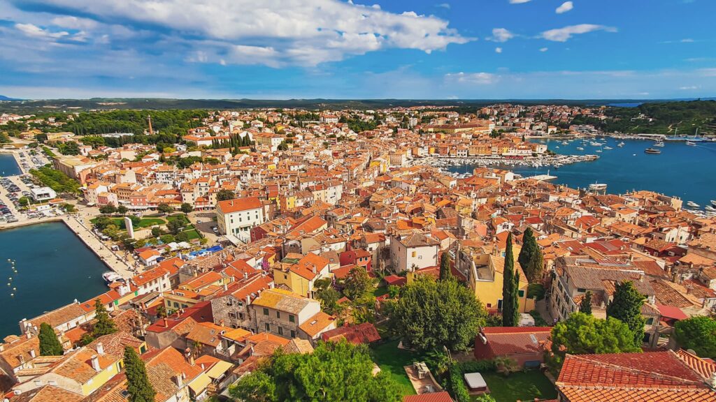 Rovinj view from bell tower Aerial view of a seaside town with dense orange rooftops and a harbor filled with boats on blue water